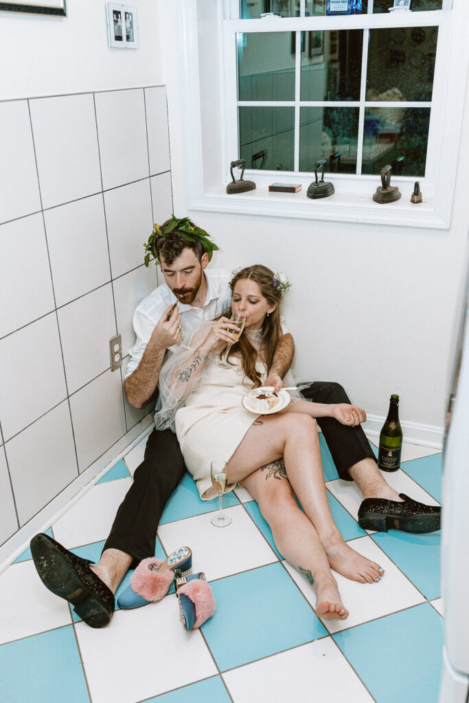 An unconventional and joyous image depicting the non-traditional portraits captured during the cake and champagne celebration in the laundry room, with blue and white tiles providing a unique canvas for iconic moments reflecting their love.