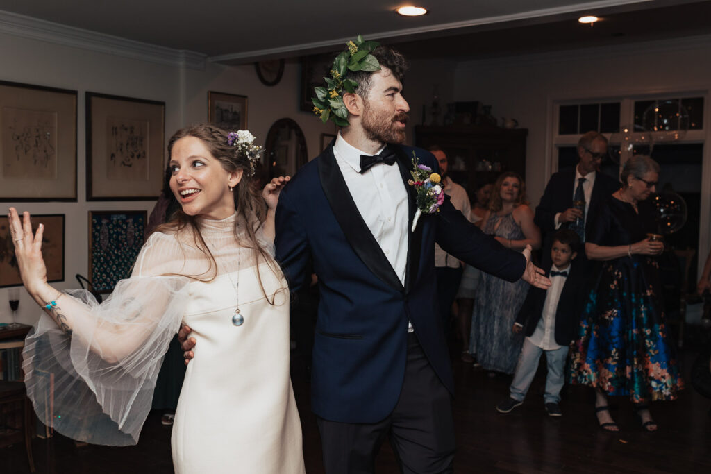 Vintage glamour on the dance floor: Bride and groom, surrounded by guests, celebrating in style with Cooper's stunning Versace and Gucci ensemble.
