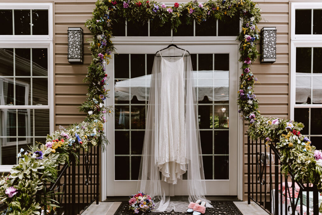 Gorgeous wedding dress hanging outsided surrounded by bold florals