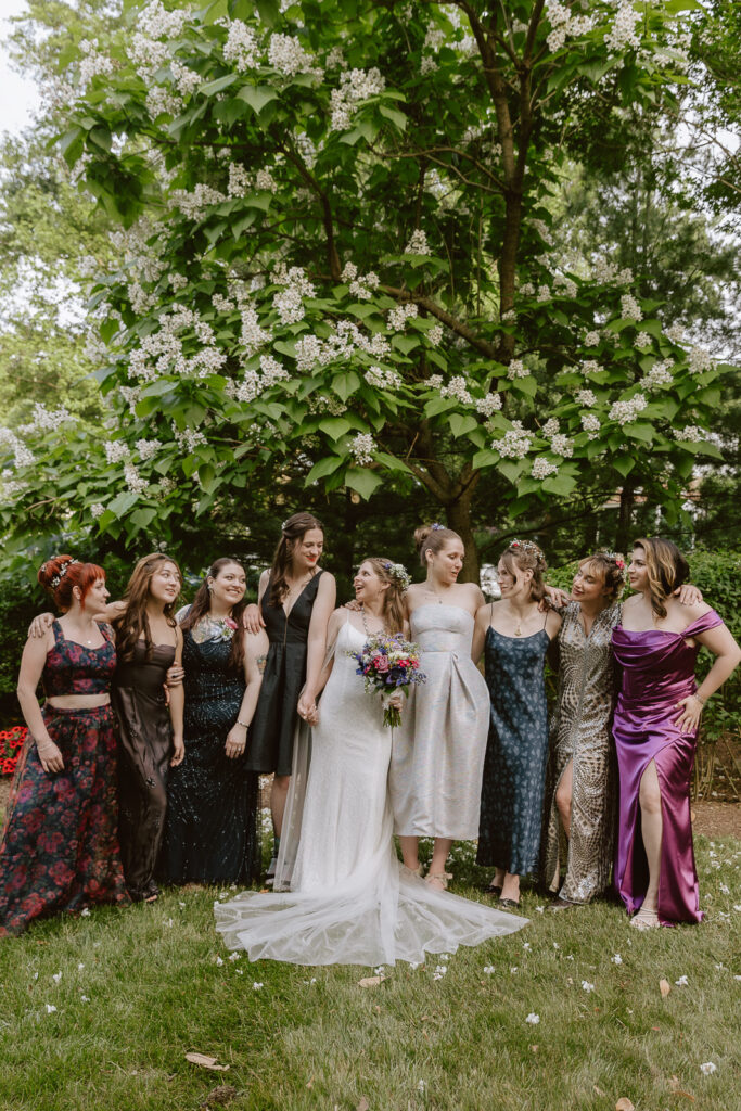 A captivating shot showcasing the unique wedding attire of the bride and her bridesmaids. The image captures the individuality of each ensemble, with a focus on the bride's stunning vintage Versace dress and the diverse styles of the bridesmaids, creating a visually appealing and personal aesthetic.