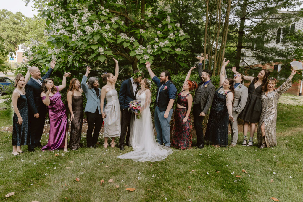 A group shot showcasing the entire bridal party in their unique and stylish wedding attire. The image reflects the cohesive yet individual fashion choices, contributing to the overall charm and personal feel of the intimate Virginia backyard wedding celebration.