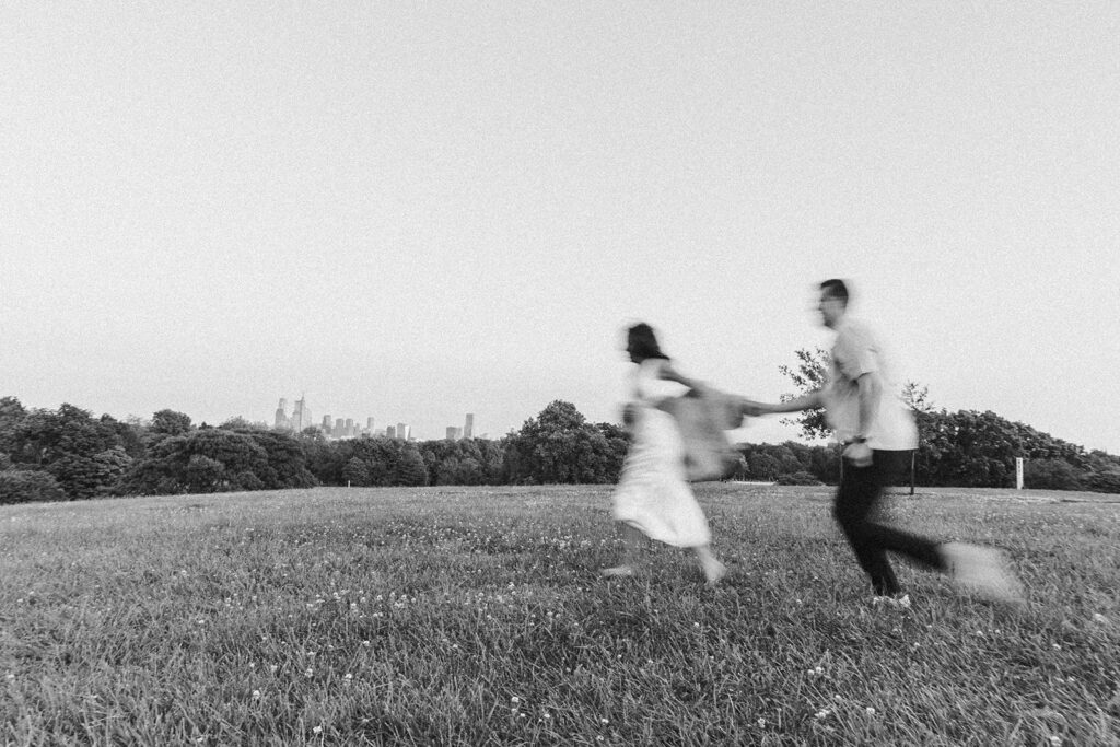 couple running in the field at belmont plateau for their engagement photos in philadelphia