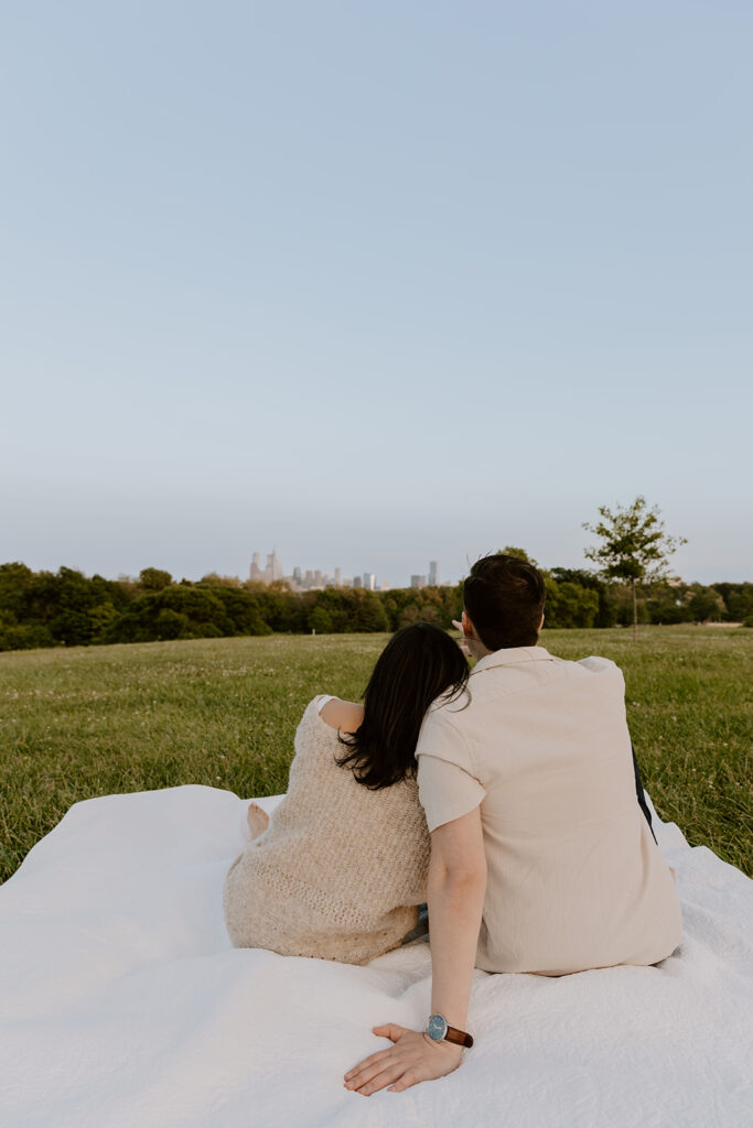 couple looking at the city skyline from belmont plateau for their engagement photos in philadelphia