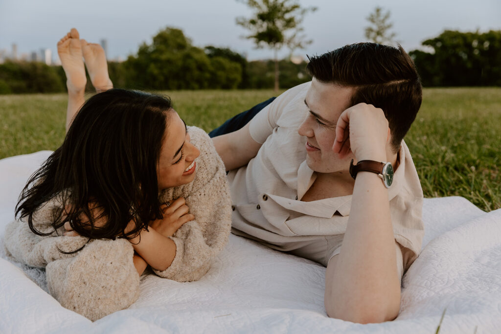 couple laying in grass at belmont plateau for their engagement photos in philadelphia