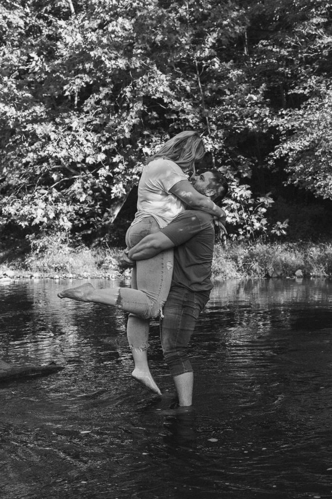 man holding woman standing in the water at their outdoor engagement photos in pennsylvania