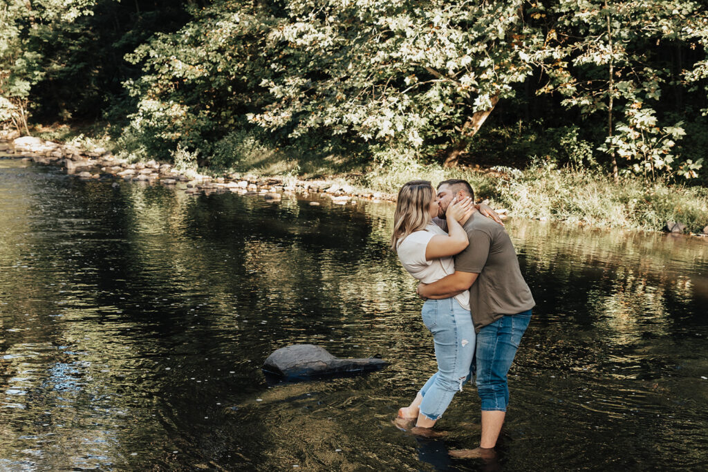 couple standing in water kissing at their outdoor engagement photos at sweet arrow lake in pennsylvania