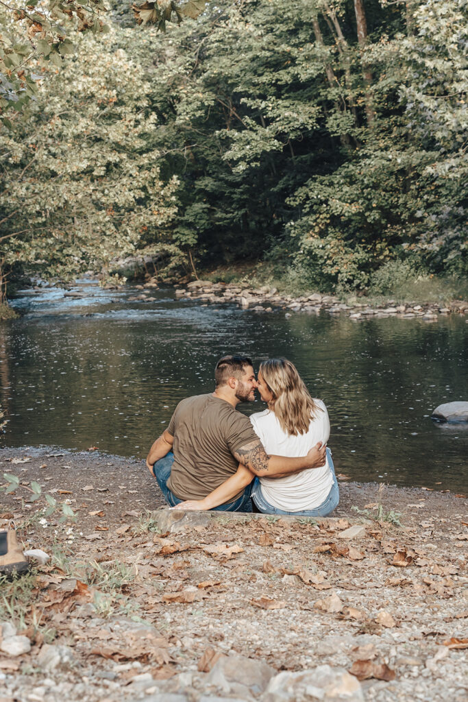 couple kissing while overlooking the water at their outdoor engagement photos in pine grove, pennsylvania
