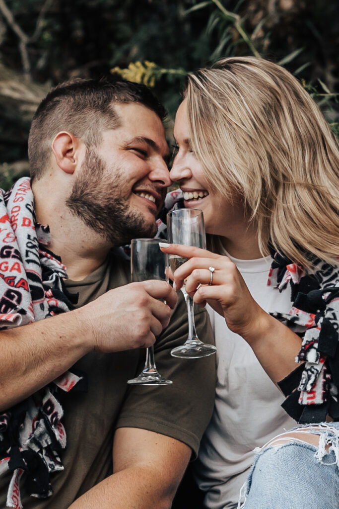 couple celebrating their engagement with champagne at outdoor engagement photos in pennsylvania