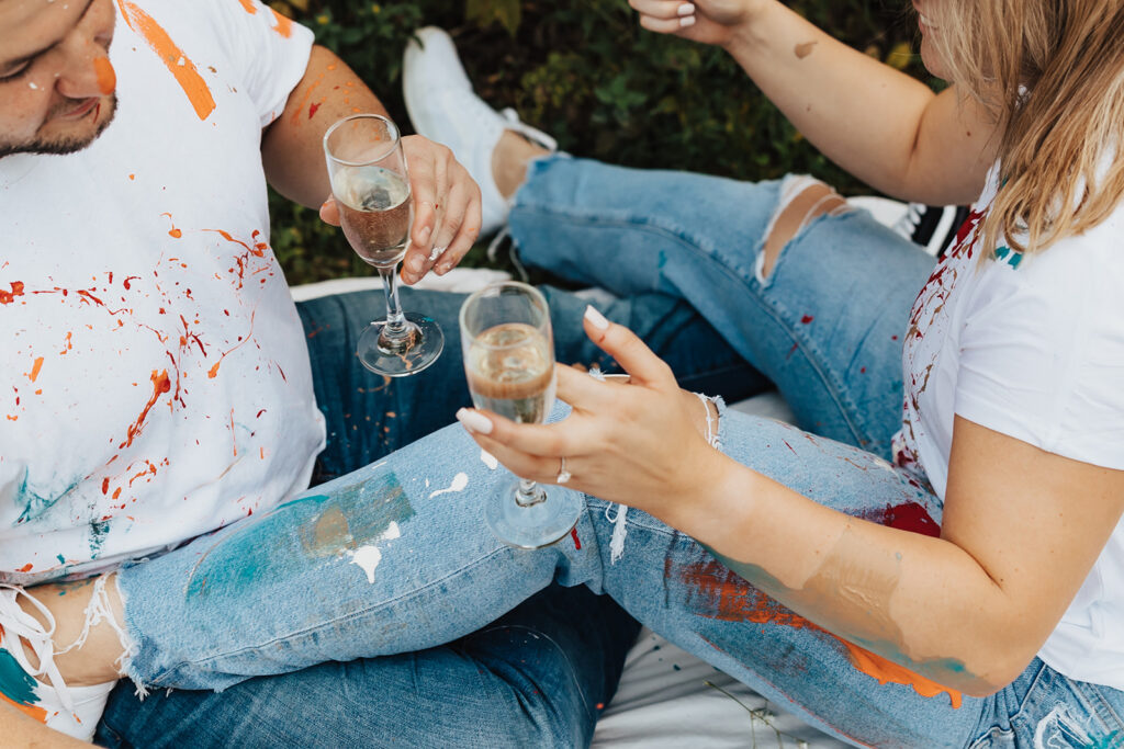 couple painting and enjoying champagne during their outdoor engagement photos