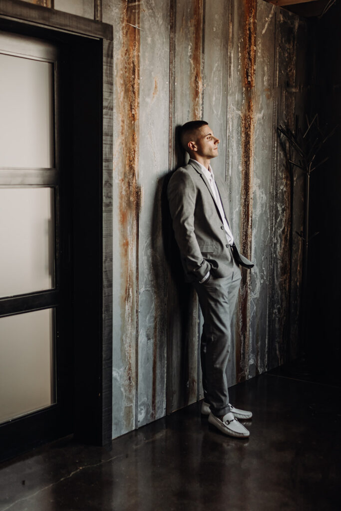 groom leaning against industrial wall at wedding venue in lebanon, pa at warehouse 435